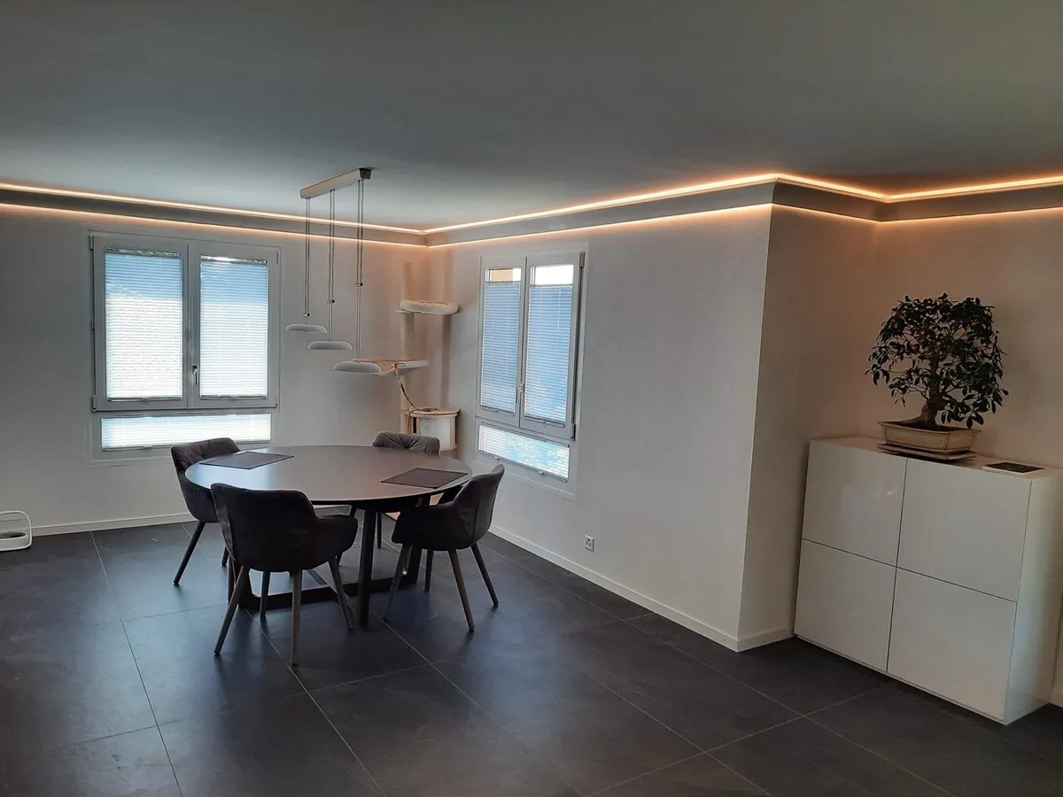 Salle à manger avec gorge lumineuse en faux plafond, deux fenêtres, table ronde et buffet blanc, réalisation Peinture Casabene.