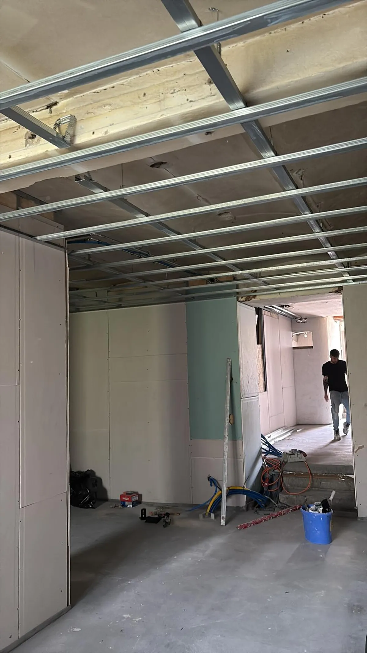 Ossature de faux plafond en cours de montage dans une grande pièce aux murs plaqués, chantier signé Peinture Casabene.