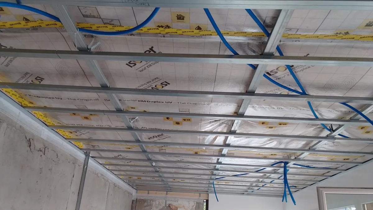 Pare-vapeur et isolation posés au plafond sous une ossature métallique suspendue, étape technique de plâtrerie avant pose des plaques.