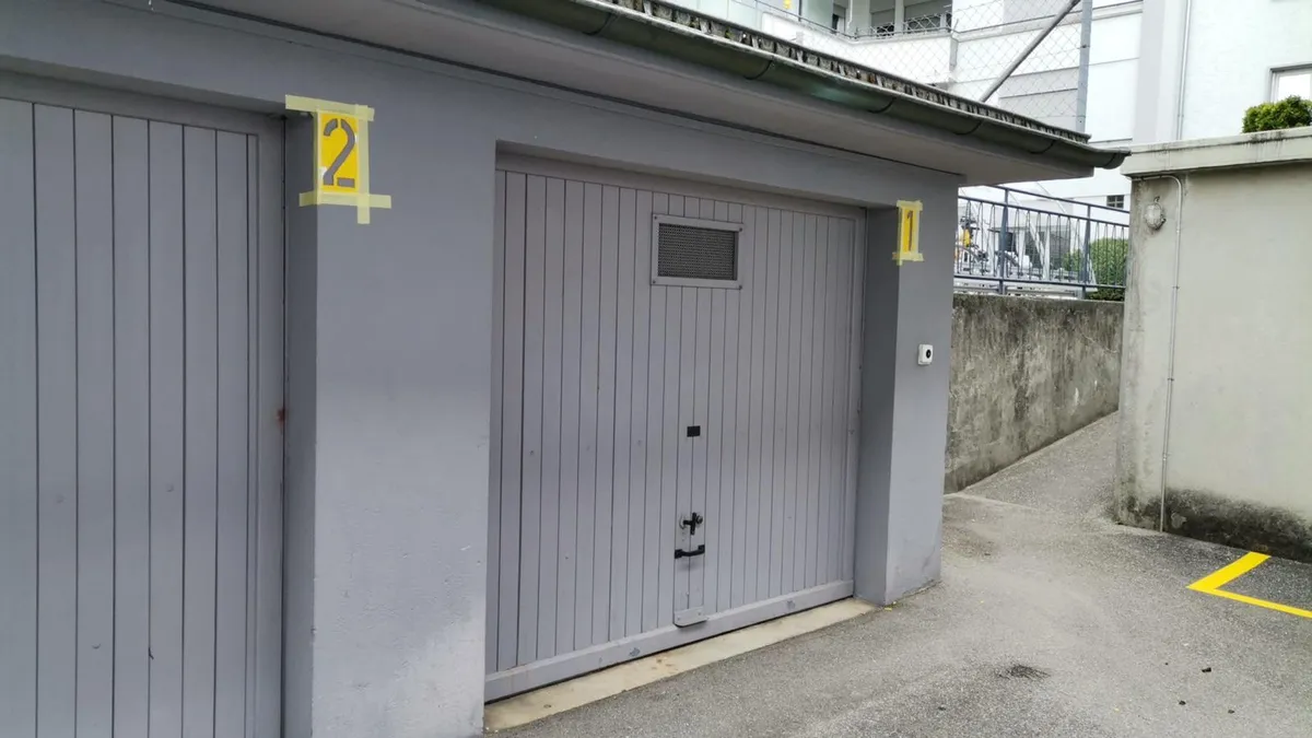 Boxes de garage aux portes repeintes et numérotées après un chantier de marquage au sol.
