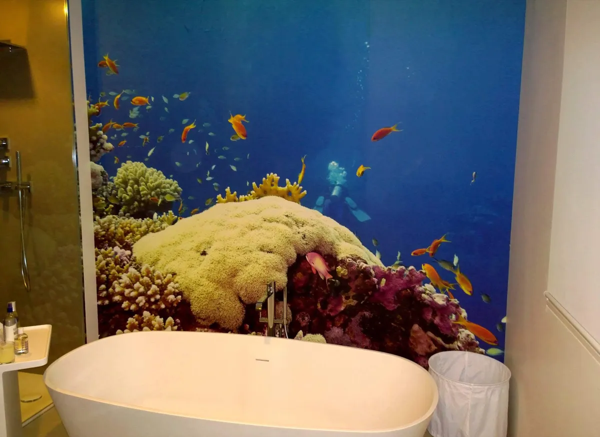 Papier peint panoramique représentant un récif corallien coloré derrière une baignoire îlot.