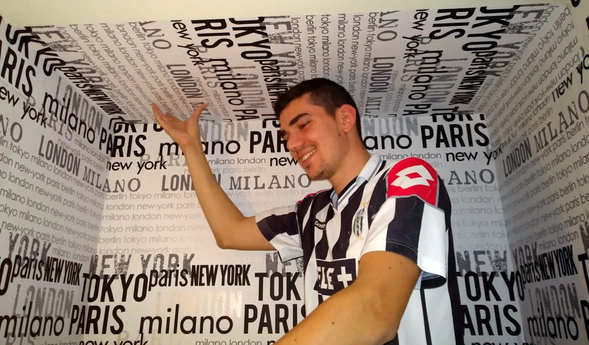 Poseur présentant d'un geste le papier peint à motif de villes fraîchement posé, une décoration murale réalisée par l'atelier Peinture Casabene.