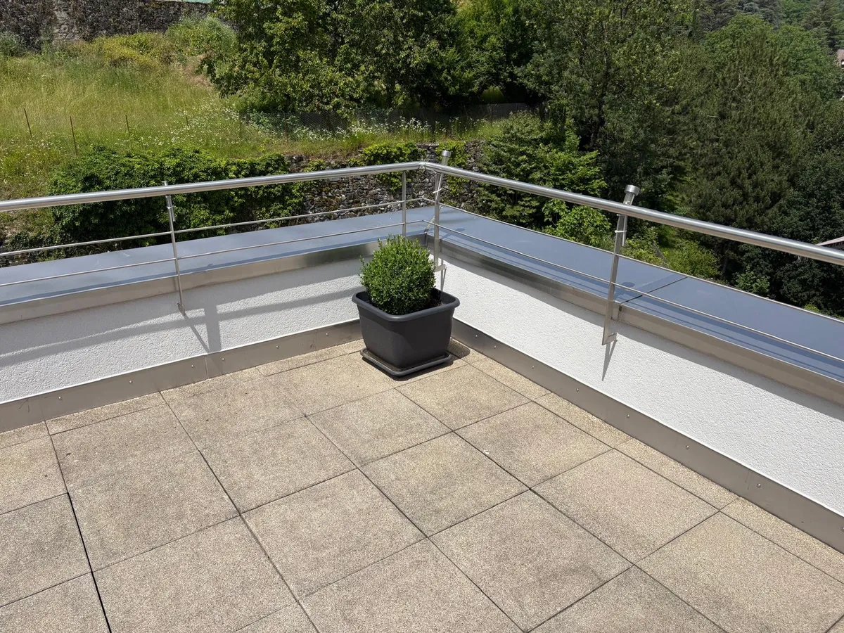 Angle de terrasse d'attique après travaux, acrotère repeint en blanc et garde-corps inox, finition de rénovation de façade dans le canton de Vaud.