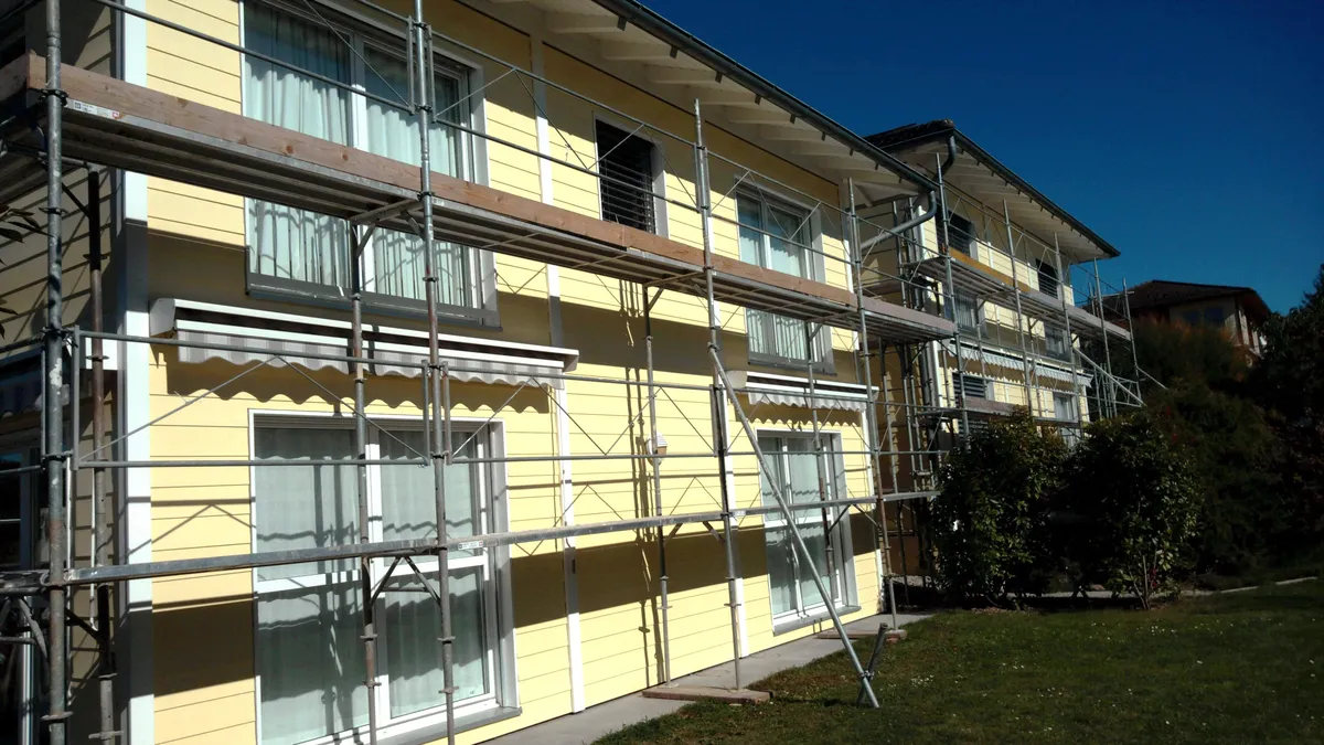 Immeuble jaune sous échafaudage pendant la rénovation de sa façade