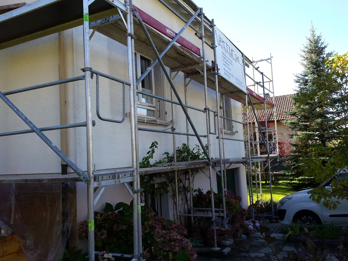 Échafaudage dressé côté jardin avec le panneau de chantier posé au pied de la façade.