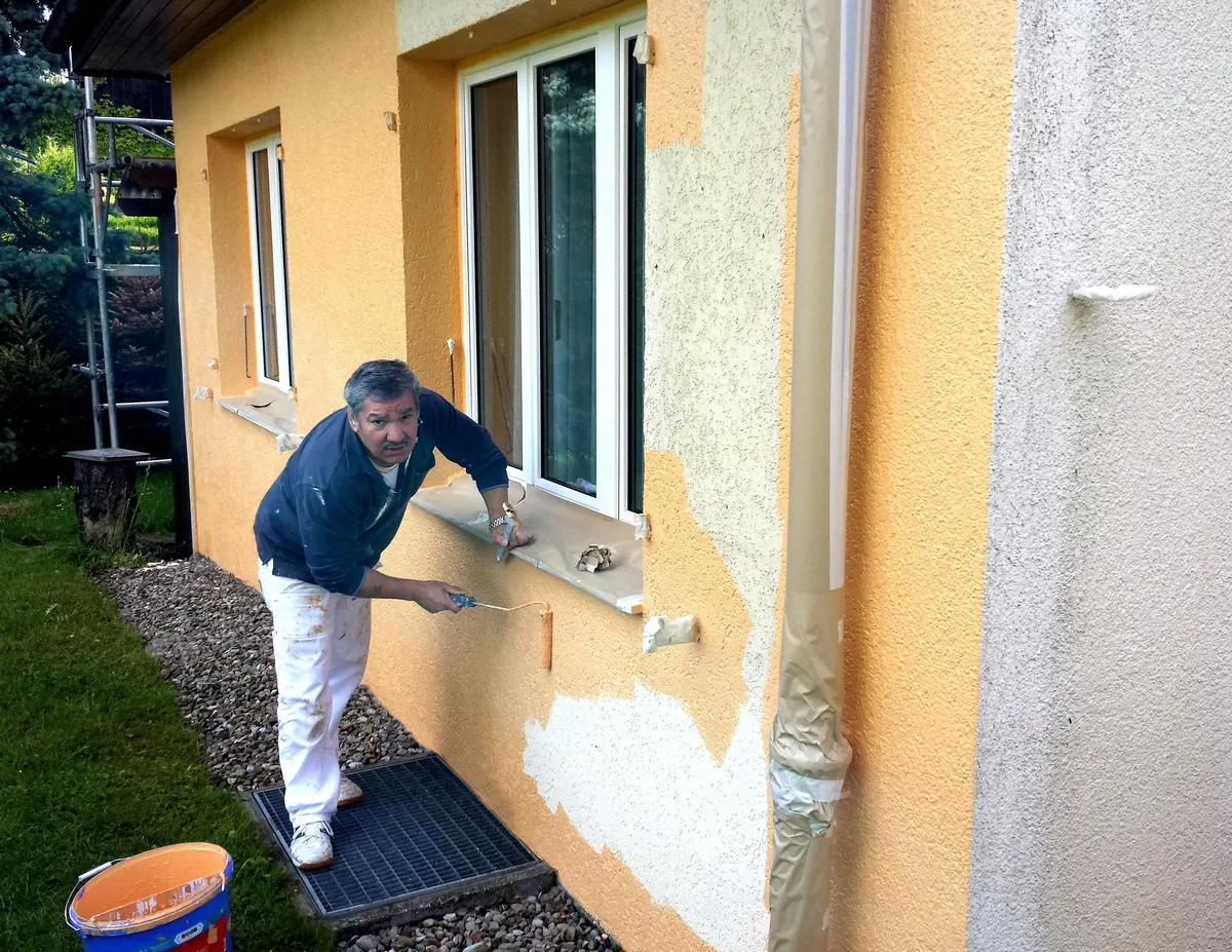 Façade jaune avec deux fenêtres, sous-couche blanche appliquée avant la finition, une étape clé de ce chantier de peinture de façade.