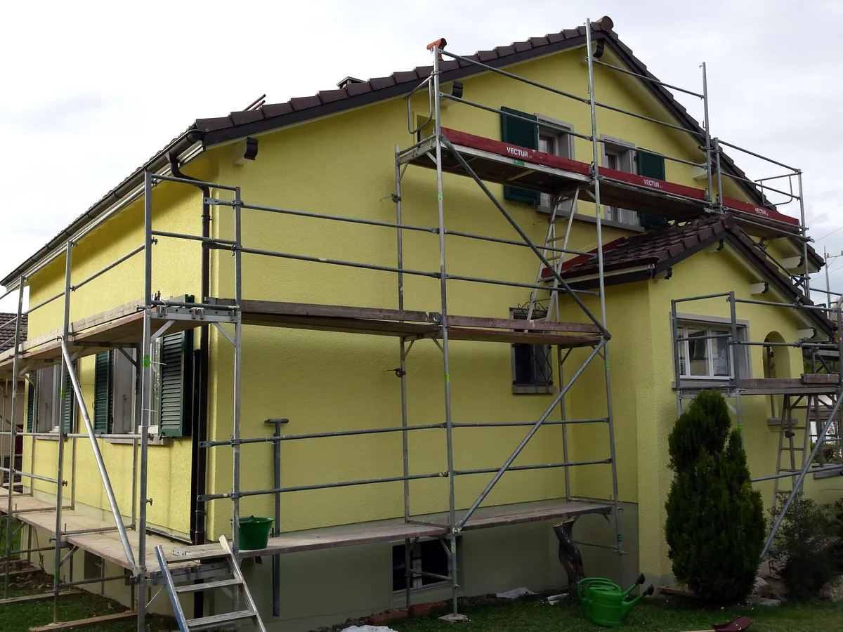 Pignon jaune équipé d'un échafaudage montant jusqu'à la toiture.