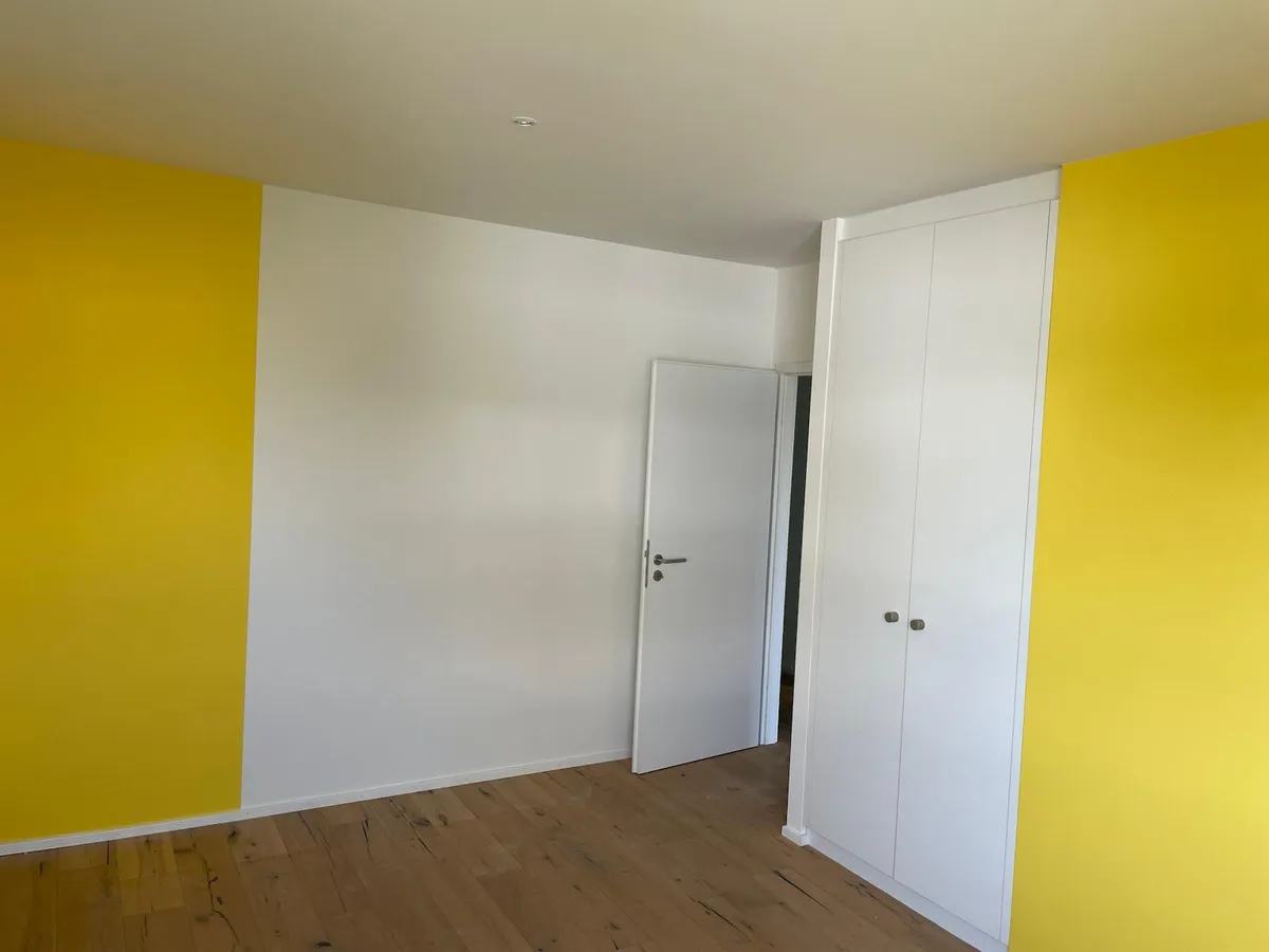 Chambre à deux murs jaunes et un mur blanc, porte et armoire blanches, parquet chêne, réalisation de peinture intérieure Casabene.