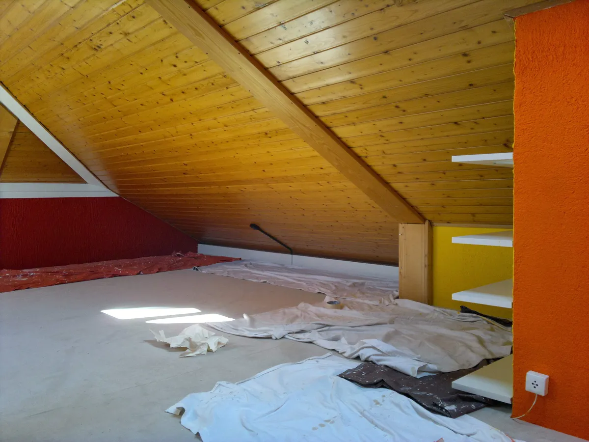 Peintre appliquant une peinture rouge dans des combles