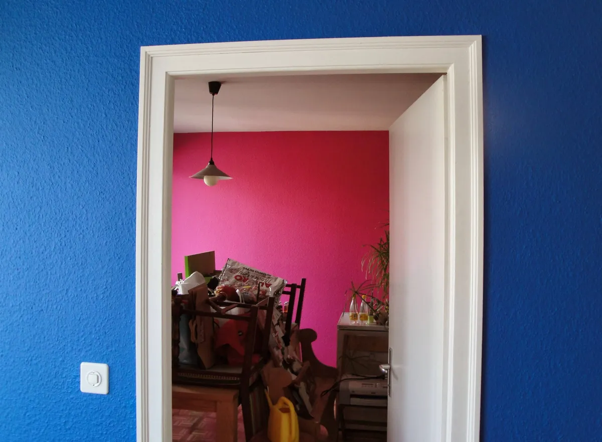 Embrasure de porte peinte en bleu dans une chambre aux murs roses, avec une suspension au plafond.