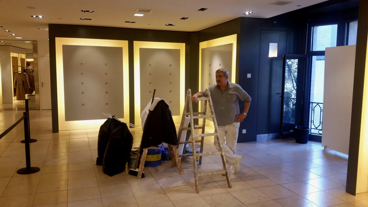 Matériel de peintre et échelle installés dans une boutique en cours de chantier.