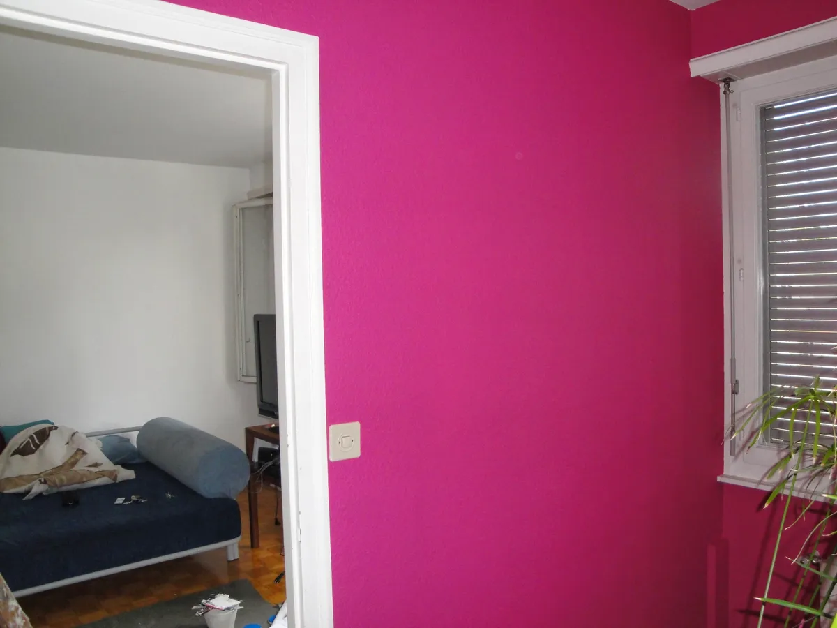 Mur de salon peint en rose fuchsia autour d'une embrasure de porte.