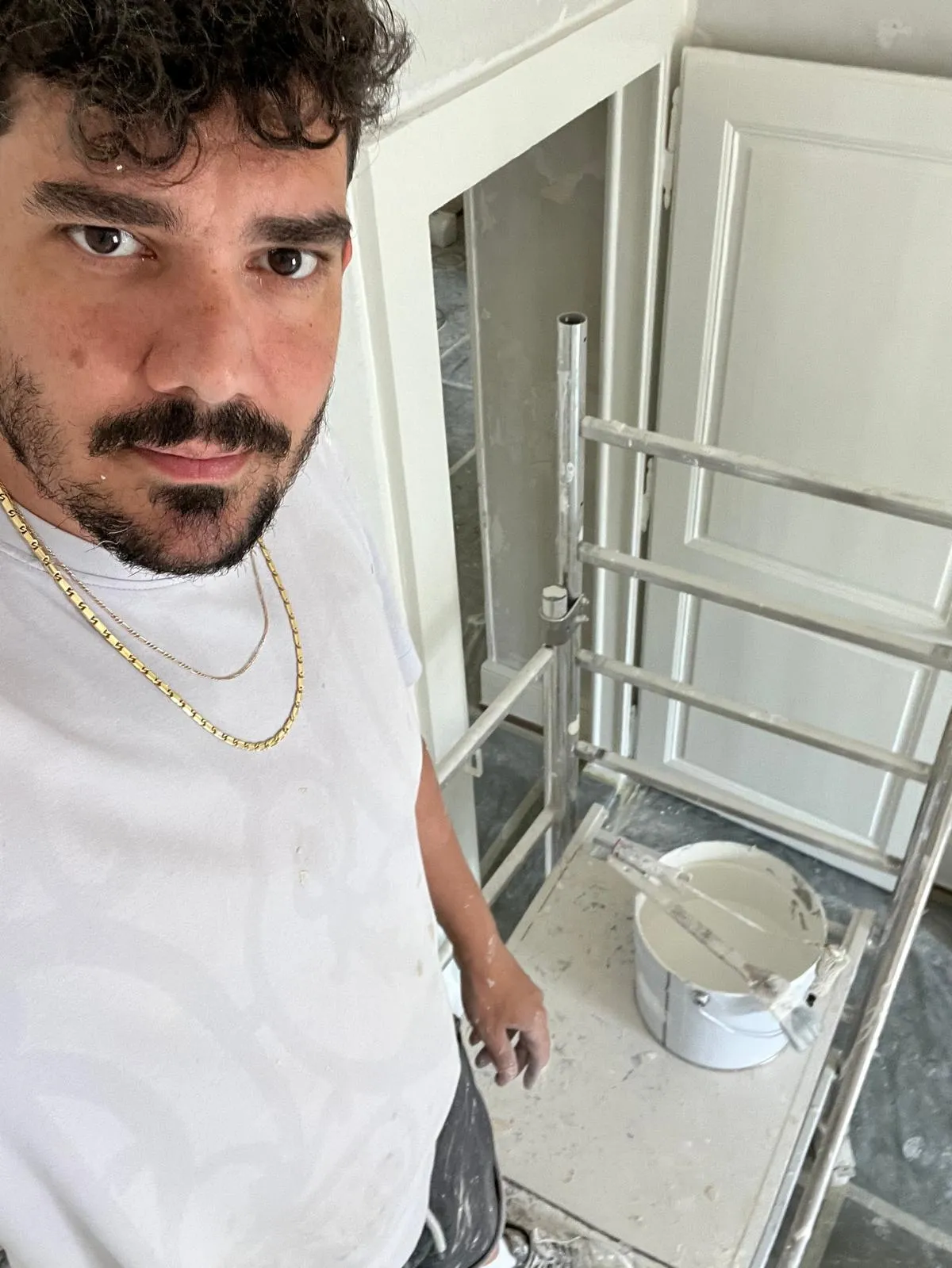 Paolo Casabene sur un chantier de rénovation intérieure, devant un échafaudage roulant et un seau de peinture, dans l'Ouest lausannois.