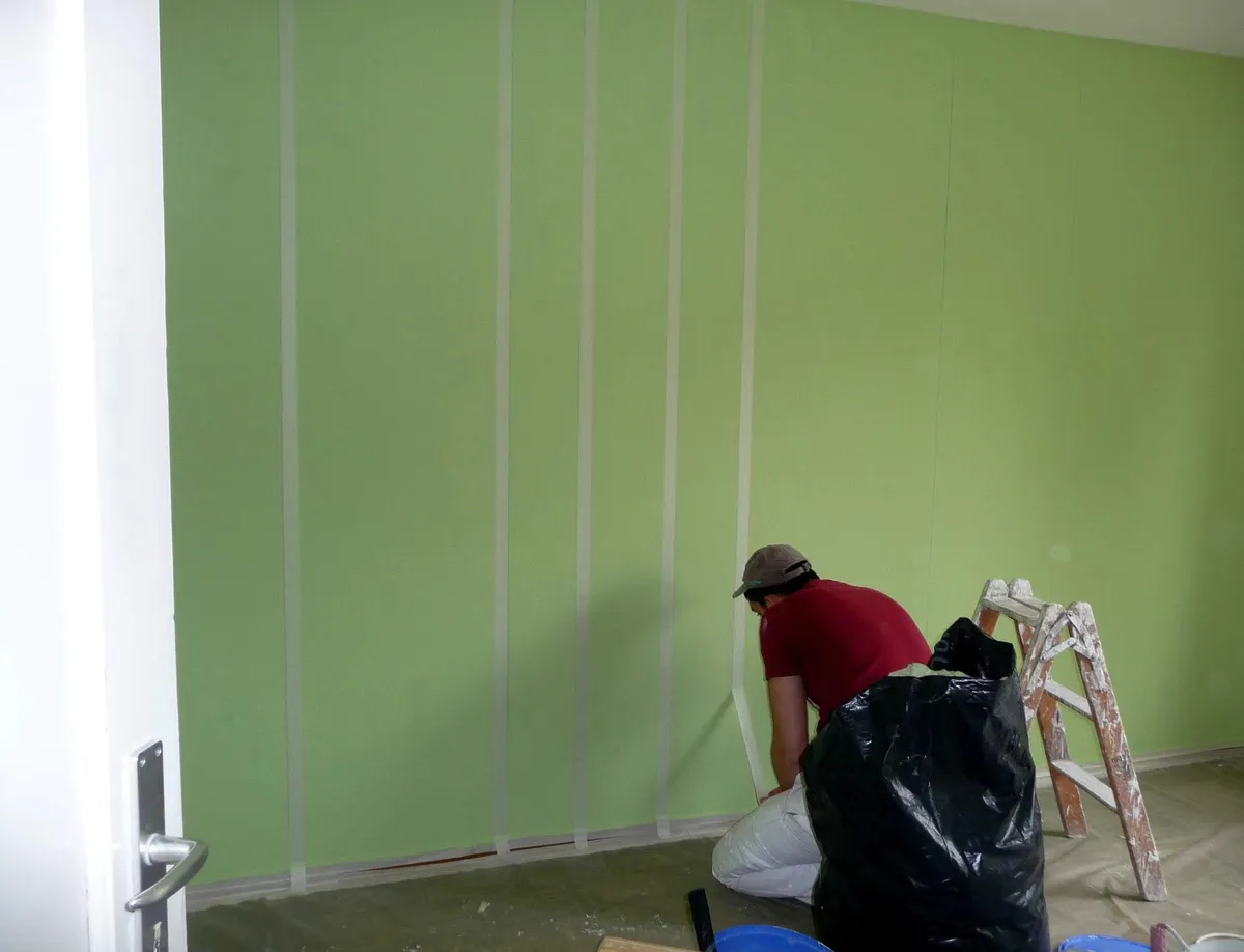 Rayures vertes en cours d'application sur le bas d'un mur intérieur.