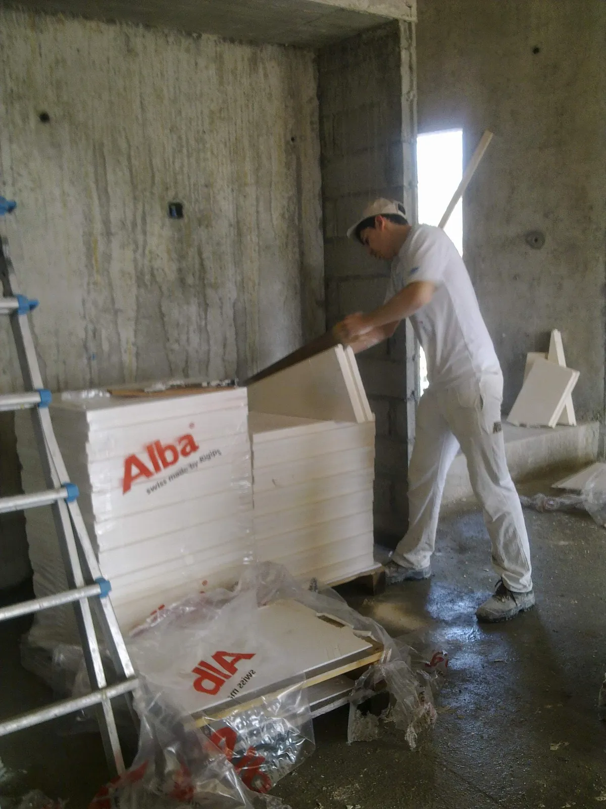 Ouvrier réceptionnant des plaques de plâtre neuves dans une pièce brute.