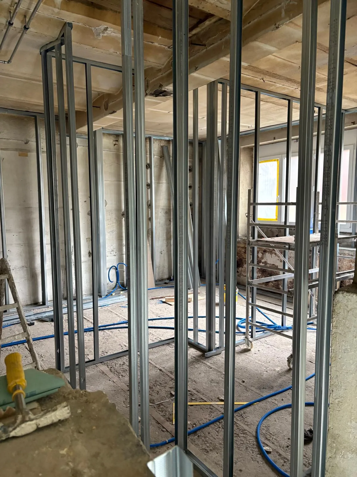 Trame de montants métalliques dessinant les futures cloisons d'un appartement en rénovation, phase de plâtrerie avant pose des plaques.